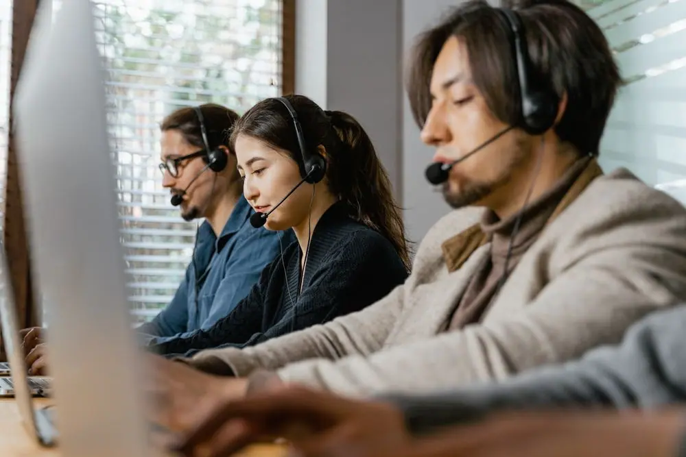 Equipo de atención al cliente con audífonos trabajando en laptops